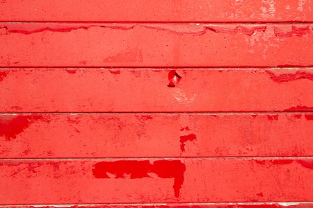 A background made of horizontal wooden slats painted in red flaking paint.の写真素材