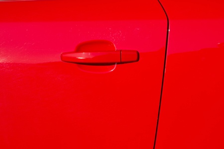 A glossy red painted car door with door edge and a handle の写真素材