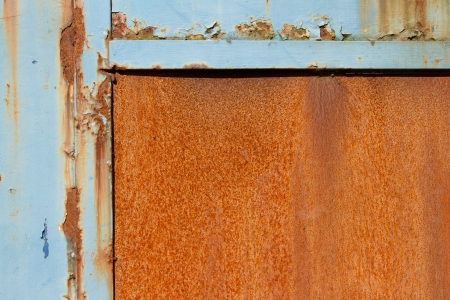 A rusty metal sheet with a half frame of blue damaged flaking paint.の写真素材