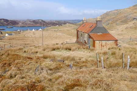 An old derelict building on moorland with tin roof and shed attached and a view to the sea and distant hills.の写真素材