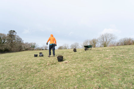 Female field worker in orange jacket working on a meadow in winterの写真素材