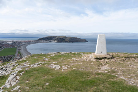Trig Point on the Little Orme, Wales, UK with a view over the seaside holiday resort of Llandudno to the Great Orme.の写真素材