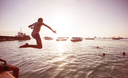 Young man jumping into the sea in Stonetown, Zanzibar.の写真素材