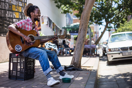 A Busker singing and playing guitar on the streets of Johannesburg.  An African man playing the guitar in the streets.Johannesburg, Gauteng, South Africa, 20018/01/10.のeditorial素材