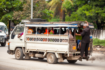 Stone Town, Zanzibar - February 8, 2017: Taxi taking people to market. Man riding on back of taxi.のeditorial素材
