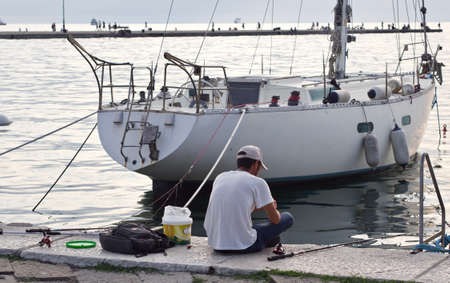 a young man is fishing on a seashoreの写真素材