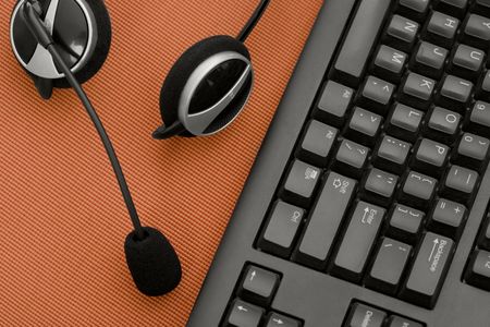 A headset and keyboard sit on a red deskの写真素材