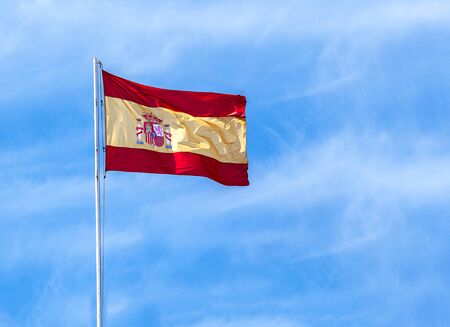 Spanish flag blowing in the wind, blue sky backgroundの写真素材