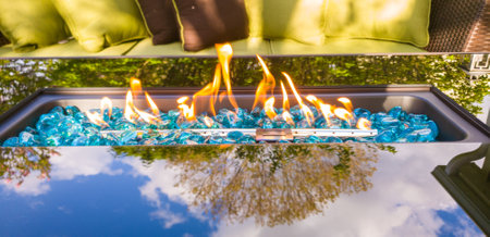 Glass Fire Table next to patio furniture and with a tree reflection on the glassの写真素材