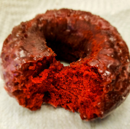 Partially-eaten Red Velvet Donut Sitting on a Paper Napkinの写真素材