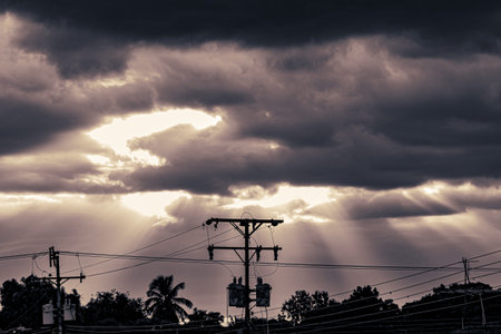 Silhouette of electricity post with dramatic sky and cloud background.の写真素材