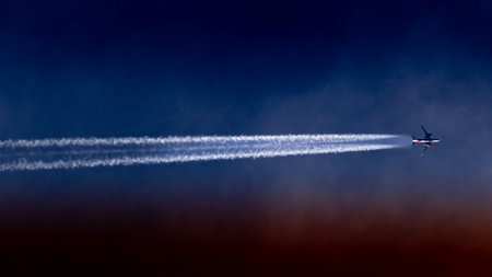 Airplane in the blue sky with white clouds and contrails.の写真素材