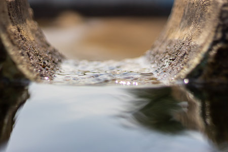 Water flowing from the pipe into a natural pond. Selective focus.の写真素材
