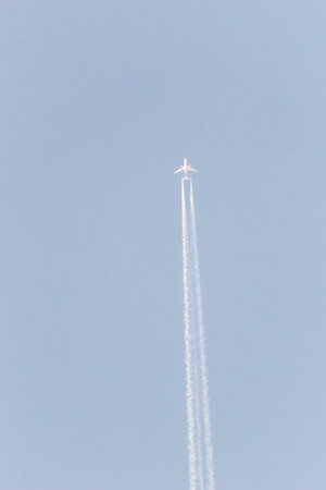 Airplane in the blue sky with contrail, closeup of photo