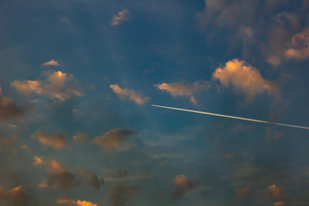 Airplane in the blue sky with clouds at sunset, background.の写真素材