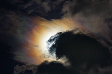 Clouds and sun in the night sky with the moon in the background