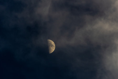 The moon in the dark night sky with clouds, natural background photoの写真素材