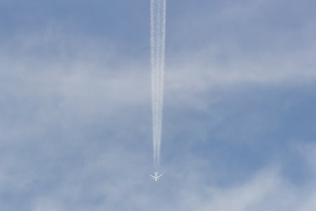 Airplane in the blue sky with white clouds and contrail.の写真素材