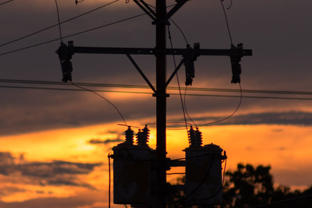 Silhouette of high voltage post with orange sunset sky background.の写真素材