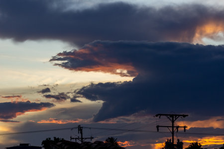 Dramatic sunset sky with dark clouds and silhouette of electric polesの写真素材