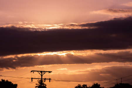 Silhouette of electric pole and sky with cloud at sunset.