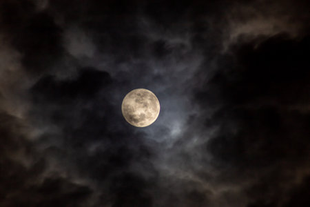 Full moon in the dark sky with clouds and stars.の写真素材