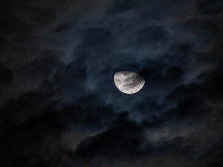 Full moon in the night sky with dark clouds. Black background.の写真素材