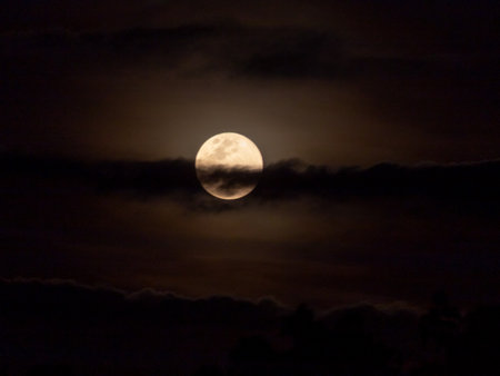 Full moon in the night sky with dark clouds, natural background.の写真素材