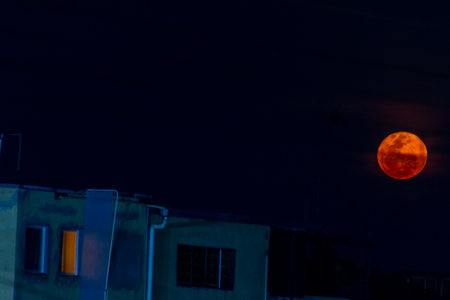 Full moon in the night sky with silhouette of houses in the cityの写真素材