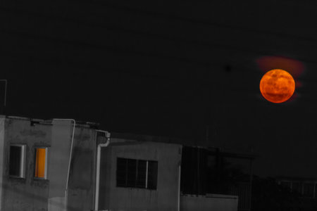 Full moon at night in the city. Orange sky on the background of houses.の写真素材