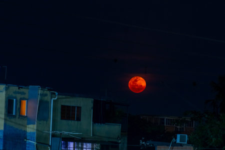 Full moon in the night sky over the roofs of the houses.