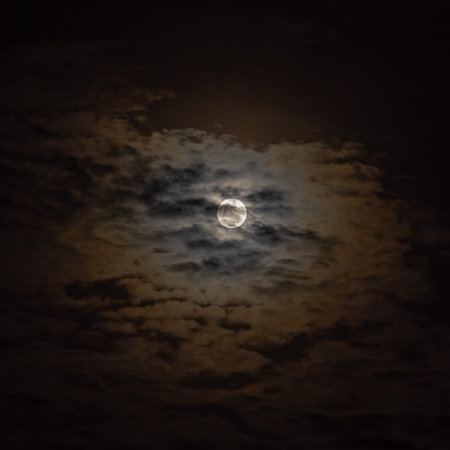 The moon in the night sky in full moonlight with clouds.