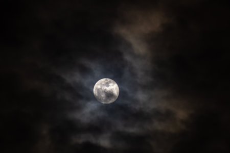 Full moon in the dark night sky with clouds.の写真素材