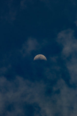 The moon in the dark blue sky with clouds in the morning.