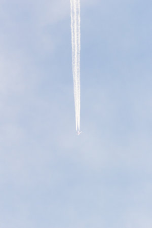 Airplane trail in the blue sky with white clouds, closeup of photoの写真素材