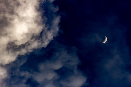 The moon in the night sky in clouds.