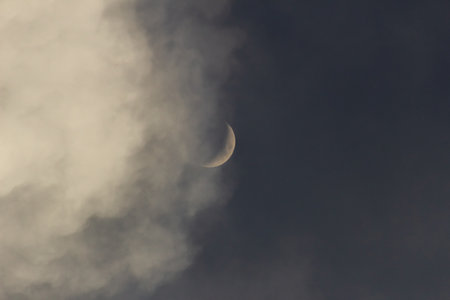 Crescent moon in the dark cloudy sky. Abstract nature background.の写真素材