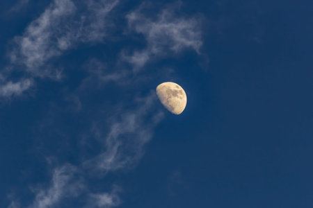 Moon in the blue sky with white clouds in the evening, closeup
