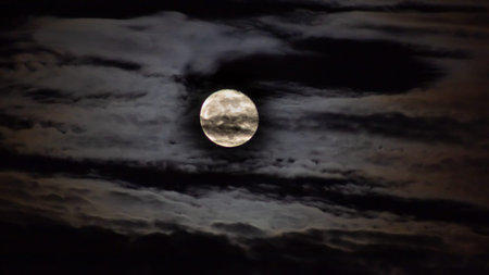 The full moon in the night sky in full moonlight and clouds
