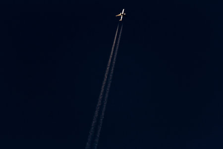 Airplane in the dark sky with a trail of white smoke.