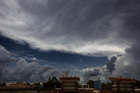clouds in the blue sky over the roofs of the houses of the cityの写真素材