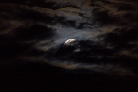 Full moon in the night sky with dark clouds, natural background.