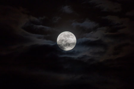 Full moon in the night sky with dark clouds. Natural background.の写真素材