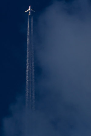 Airplane in the sky with clouds and trail of an airplane.