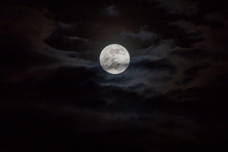 Full moon in the dark night sky with clouds, nature background.