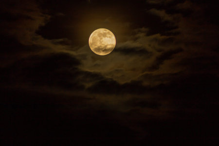 Full moon in the night sky with clouds. Natural background and texture.