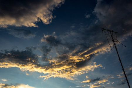 Dramatic sunset sky with clouds and silhouette of electricity pylonの写真素材