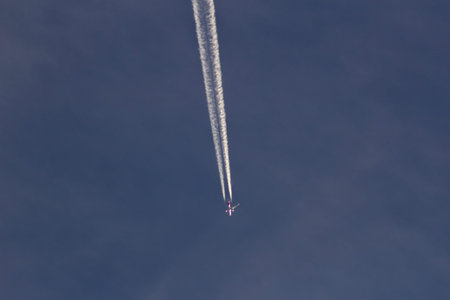 Aerobatic aircraft in the blue sky with white clouds.
