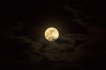 The full moon in the night sky with dark clouds. The full moon in the night sky.