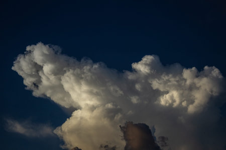 Dramatic cloudscape with dark blue sky and white clouds.